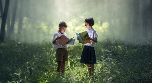 Dos niños leyendo en el bosque.