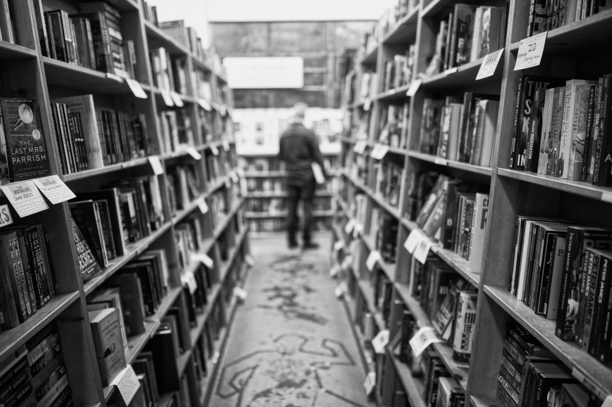 Foto en escala de grises de un hombre en una biblioteca
