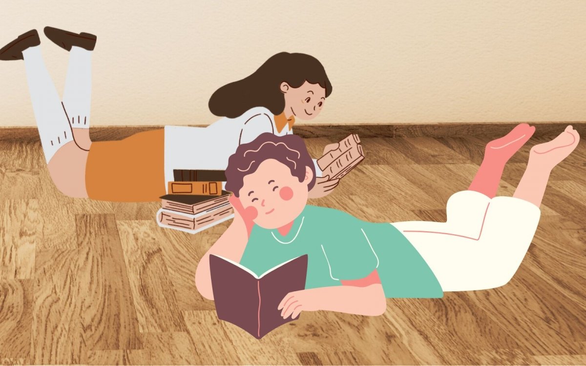 Un chico y una chica tumbados en el suelo leyendo cada uno un libro