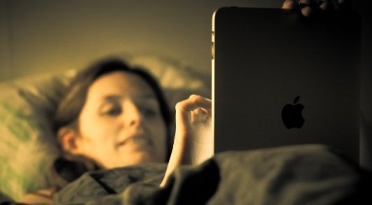 Mujer leyendo con un iPad en la cama antes de dormir