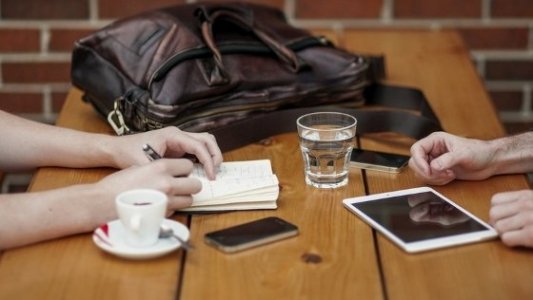 Intercambio de ideas junto a un café, un móvil y una tablet.