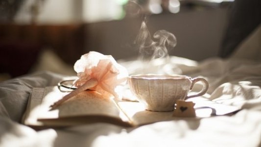 Taza de té sobre un libro con una flor de papel.