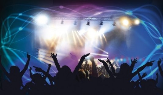 Imagen a contraluz de gente bailando en un concierto.