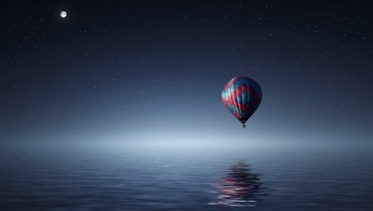 Globo flotando sobre un mar de fantasía con la luna al fondo.