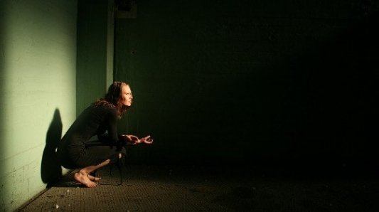 Mujer sentada en la oscuridad de un callejón