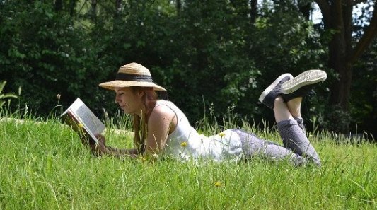 Chica joven leyendo un libro en el campo.