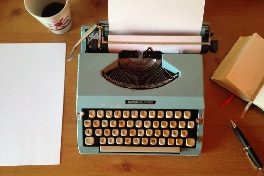 Máquina de escribir, café y libreta.