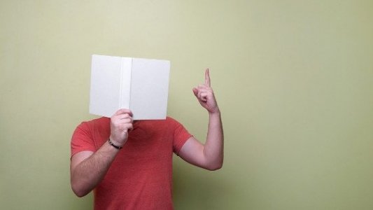 Persona cubriéndose el rostro con un libro.