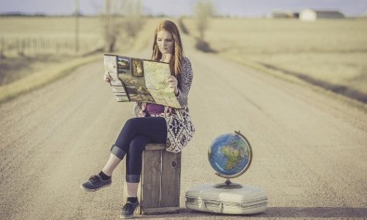 Mujer joven leyendo un mapa en un viaje por carretera con una bola del mundo.