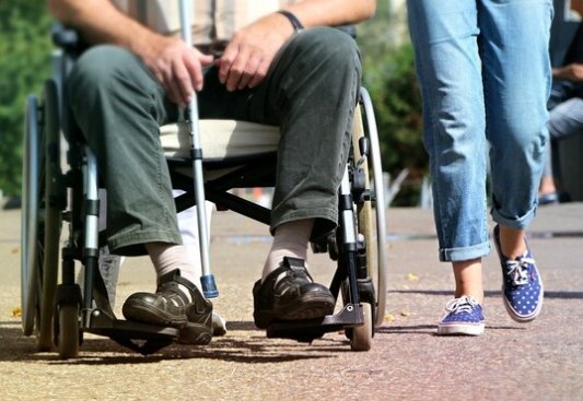 Hombre en silla de ruedas con bastón junto a una mujer