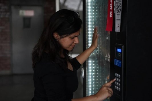 Mujer tecleando en una máquina expendedora