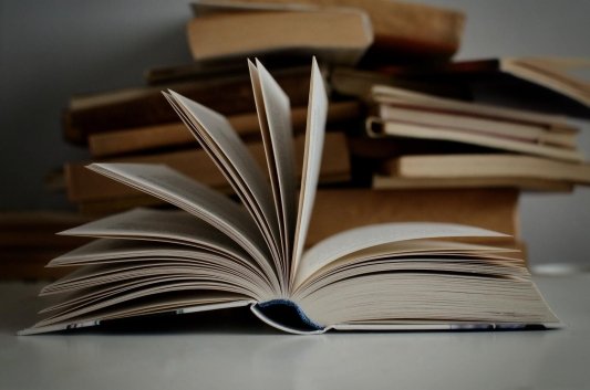 Libro abierto frente a pila de libros