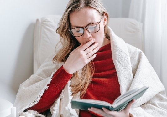 Mujer bostezando mientras lee un libro