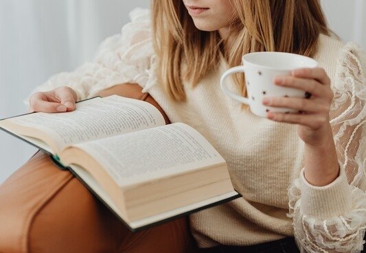 Mujer leyendo un libro con una taza en la mano