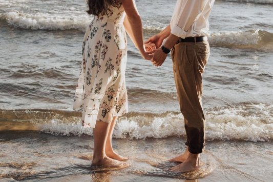 Una pareja se coge de las manos en la orilla de la playa